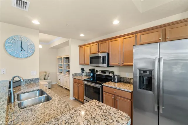 a kitchen with stainless steel appliances granite countertop a refrigerator sink and stove