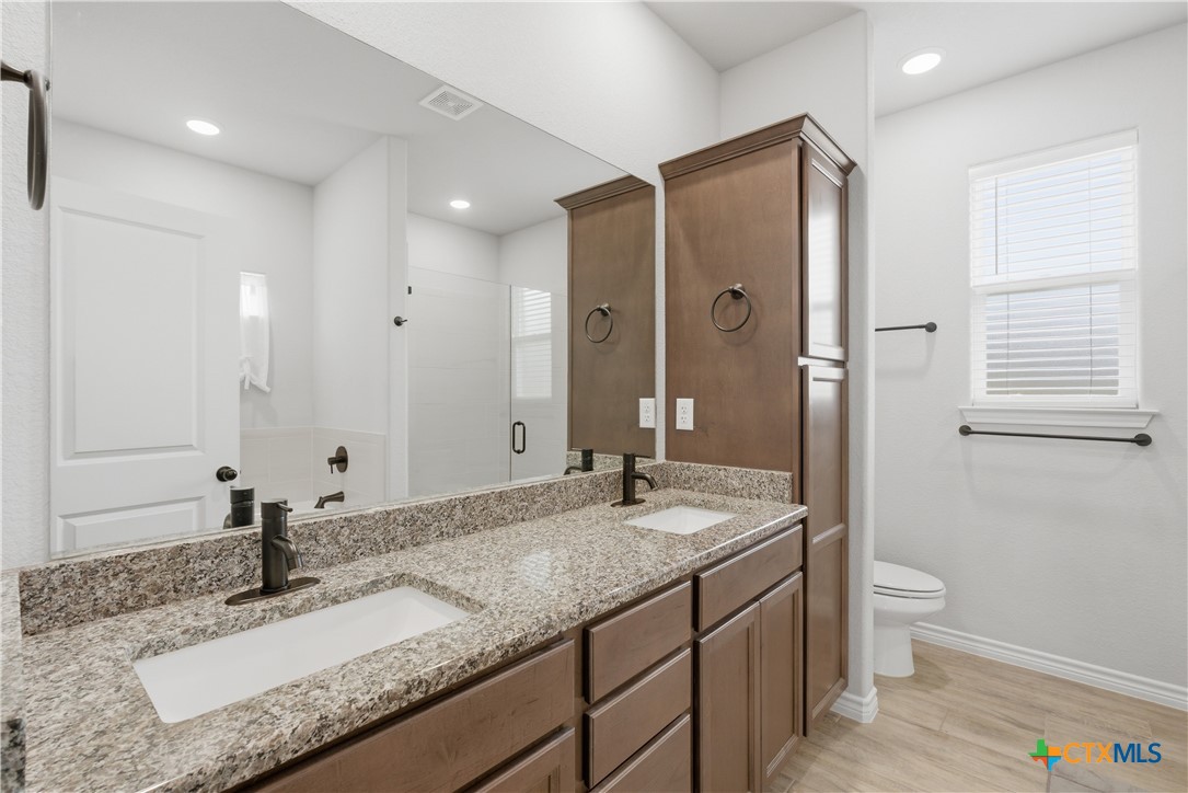 3201 Hedwig Street Killeen, TX 76549 - Photo 17 of 38 a bathroom with a granite countertop sink a toilet a large mirror and shower