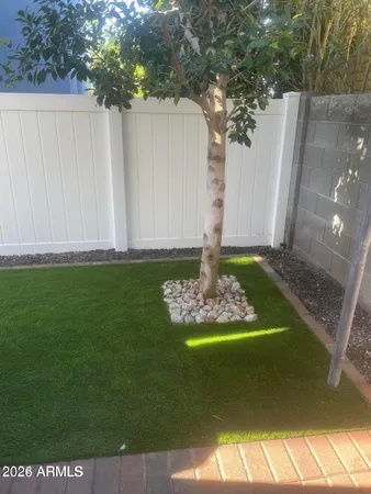 a view of a backyard with large trees and wooden fence