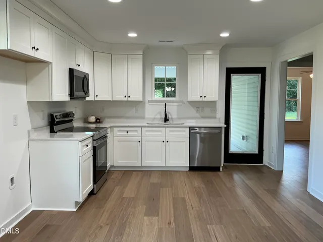 a kitchen with a white cabinets a sink dishwasher and a stove with wooden floor