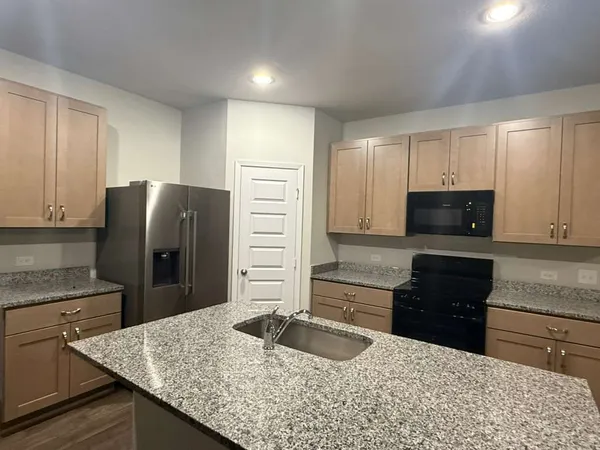 a kitchen with stainless steel appliances granite countertop a refrigerator a stove and a sink