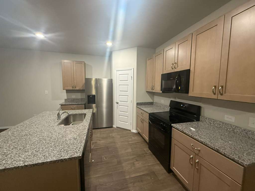 2711 Totley Road Manor, TX 78653 - Photo 13 of 40 a kitchen with a sink microwave and refrigerator