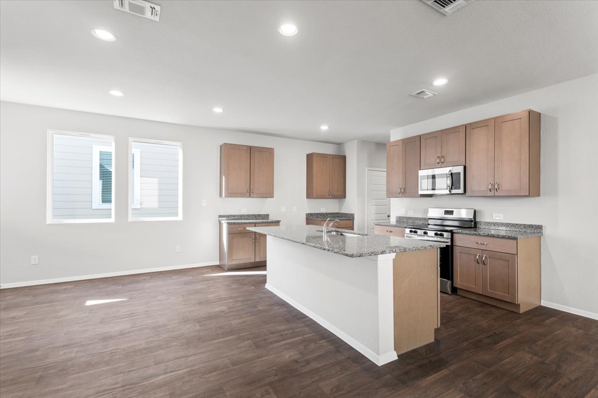 2711 Totley Road Manor, TX 78653 - Photo 14 of 40 a kitchen with stainless steel appliances granite countertop a stove top oven a sink dishwasher and a refrigerator with wooden floor