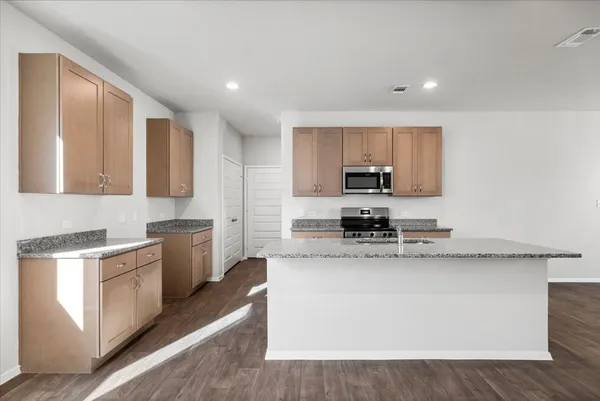 a kitchen with stainless steel appliances granite countertop a stove a sink and a microwave