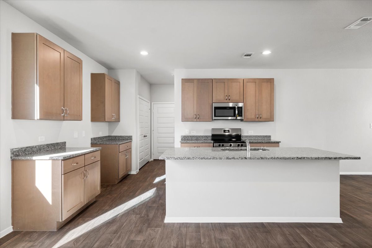 2711 Totley Road Manor, TX 78653 - Photo 18 of 40 a kitchen with stainless steel appliances granite countertop a stove a sink and a microwave