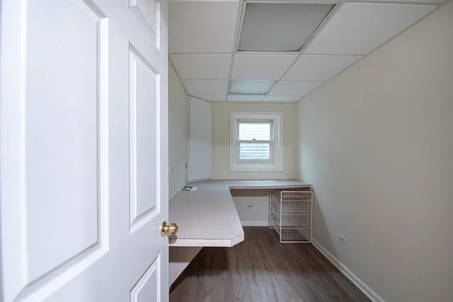 an empty room with wooden floor staircase and kitchen view