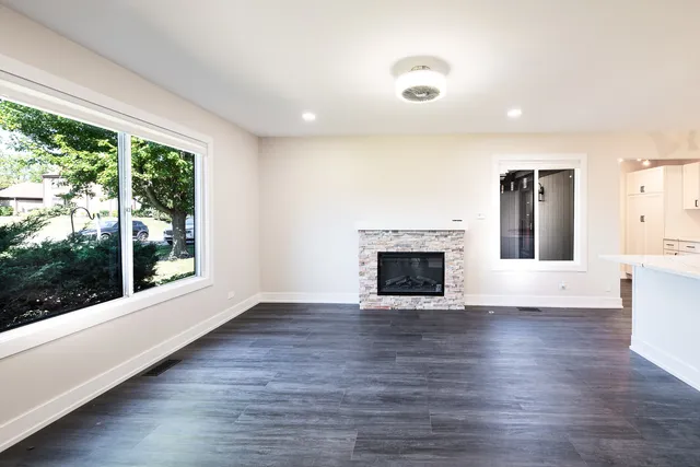 an empty room with wooden floor fireplace and windows