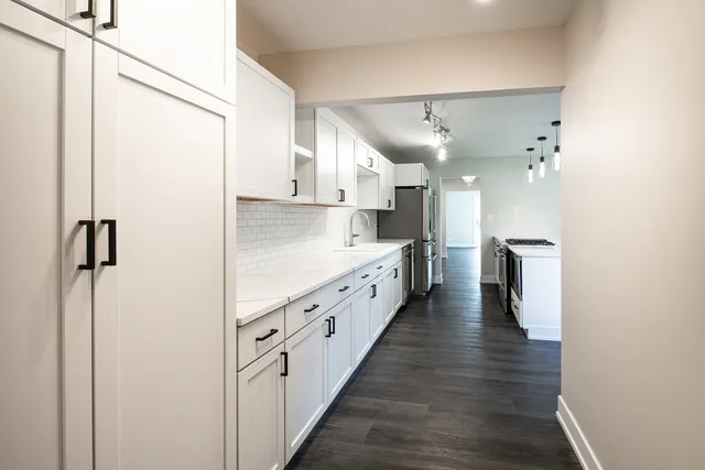 a kitchen with granite countertop a stove oven a sink dishwasher and white cabinets with wooden floor