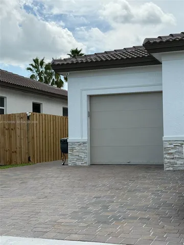 a view of a house with a wooden fence and a pathway