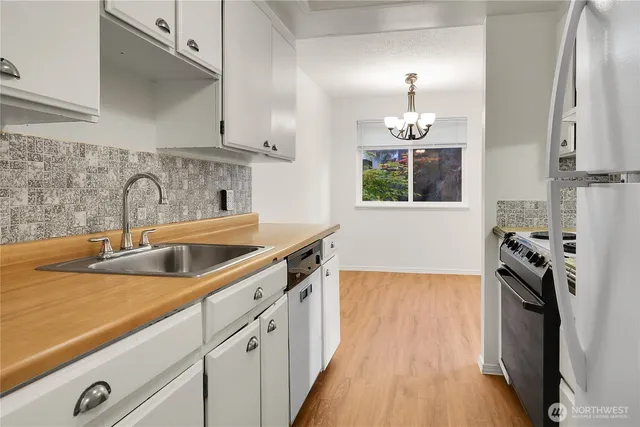 a kitchen with stainless steel appliances a sink stove and wooden floor