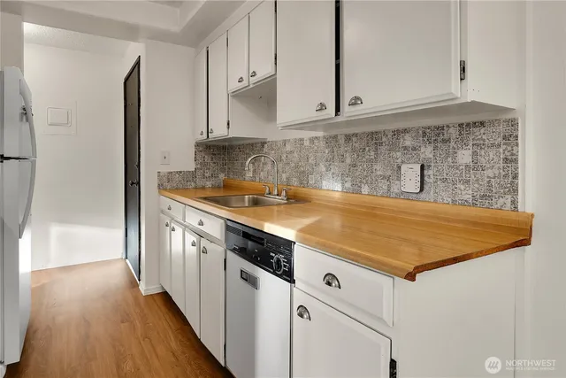 a kitchen with stainless steel appliances granite countertop a sink and cabinets with wooden floor