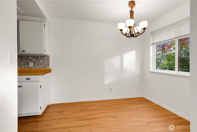 a view of a room with wooden floor chandelier and windows