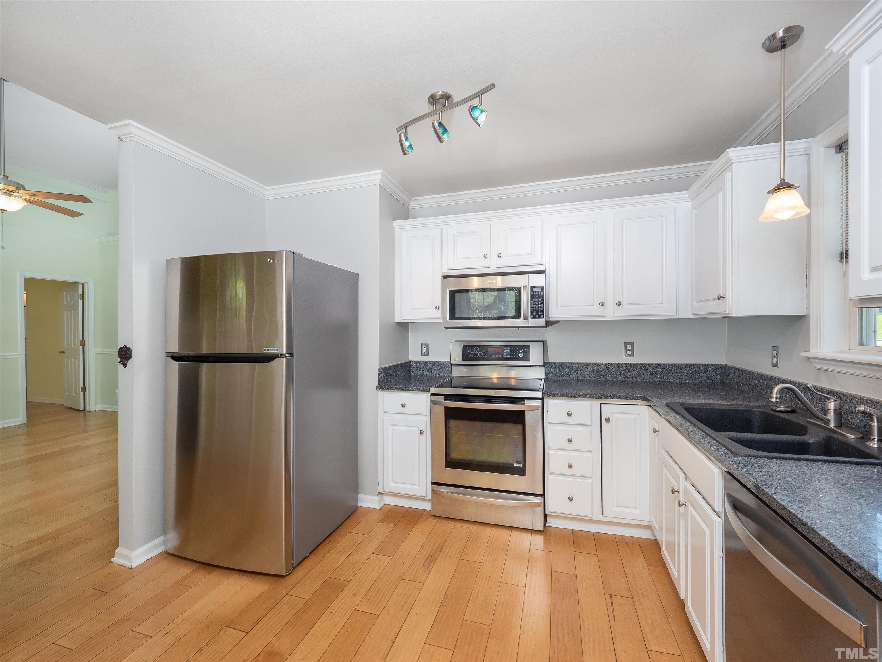 818 Shackleton Road Apex, NC 27502 - Photo 11 of 20 a kitchen with stainless steel appliances granite countertop a refrigerator a stove a sink and white cabinets with wooden floor