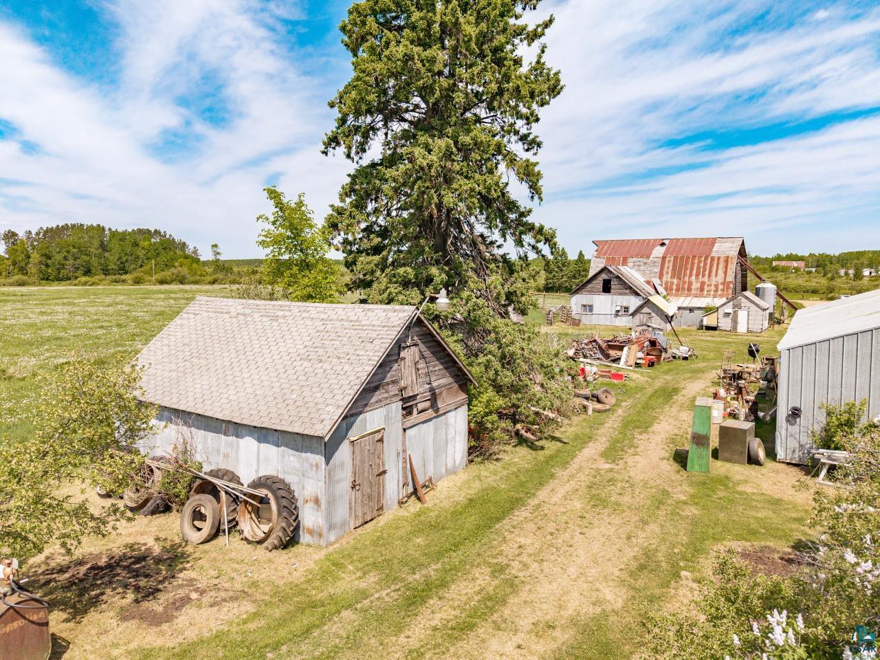 6606 Metso Road Kettle River, MN 55757 - Photo 41 of 84 Rural property featuring multiple outbuildings, a gravel driveway, mature trees, and expansive green fields