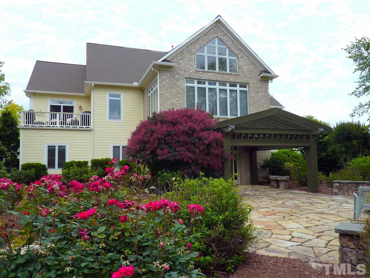 A stone wall surrounds the large circular stone patio. The grand pergola and exquisite landscaping are an inviting preview of the home's luxurious interior.