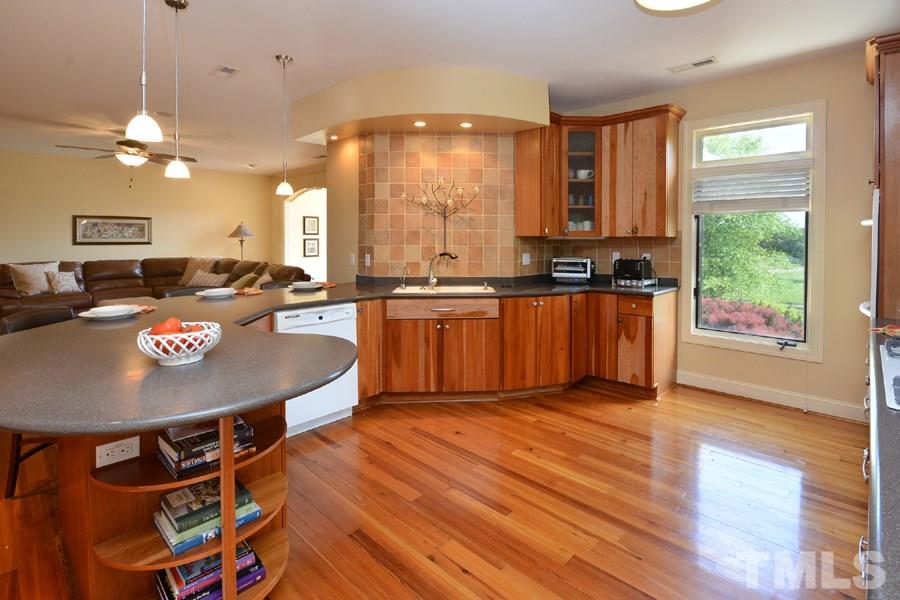 7016 Holly Ridge Road Rougemont, NC 27572 - Photo 15 of 24 Warm toned Corian surfaces, travertine tiled back splashes, custom solid cherry cabinets, deep pantry and copious storage, Whirlpool appliances, surrounded by a curved bar perfect for entertaining.