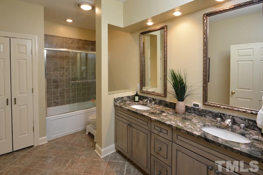 7016 Holly Ridge Road Rougemont, NC 27572 - Photo 21 of 24 Dual ceramic sinks set in rich green-hued granite, tiled deep whirlpool tub, linen closet, and stone tiled flooring.