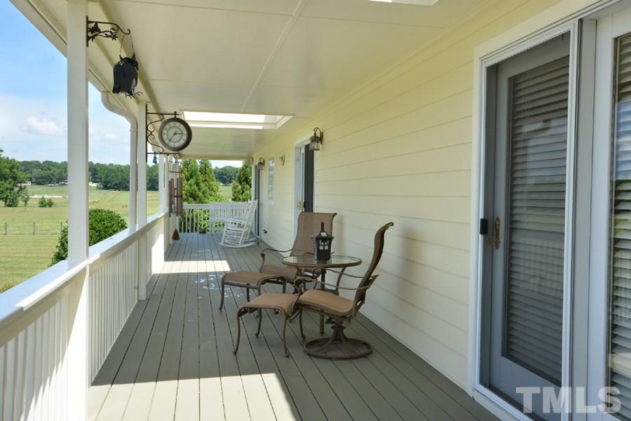 7016 Holly Ridge Road Rougemont, NC 27572 - Photo 4 of 24 The serene rocking chair back porch overlooks the riding arena and vast back acreage. Four French doors open to the living room, guest room, office, and master bedroom. Outside stairs lead down to the blacktop parking area.
