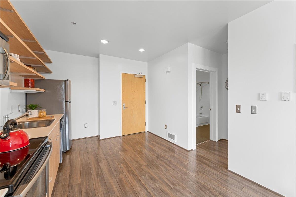 1201 Pine Street, Unit 365 Oakland, CA 94607 - Photo 14 of 33 a view of a kitchen with a fridge and wooden floor