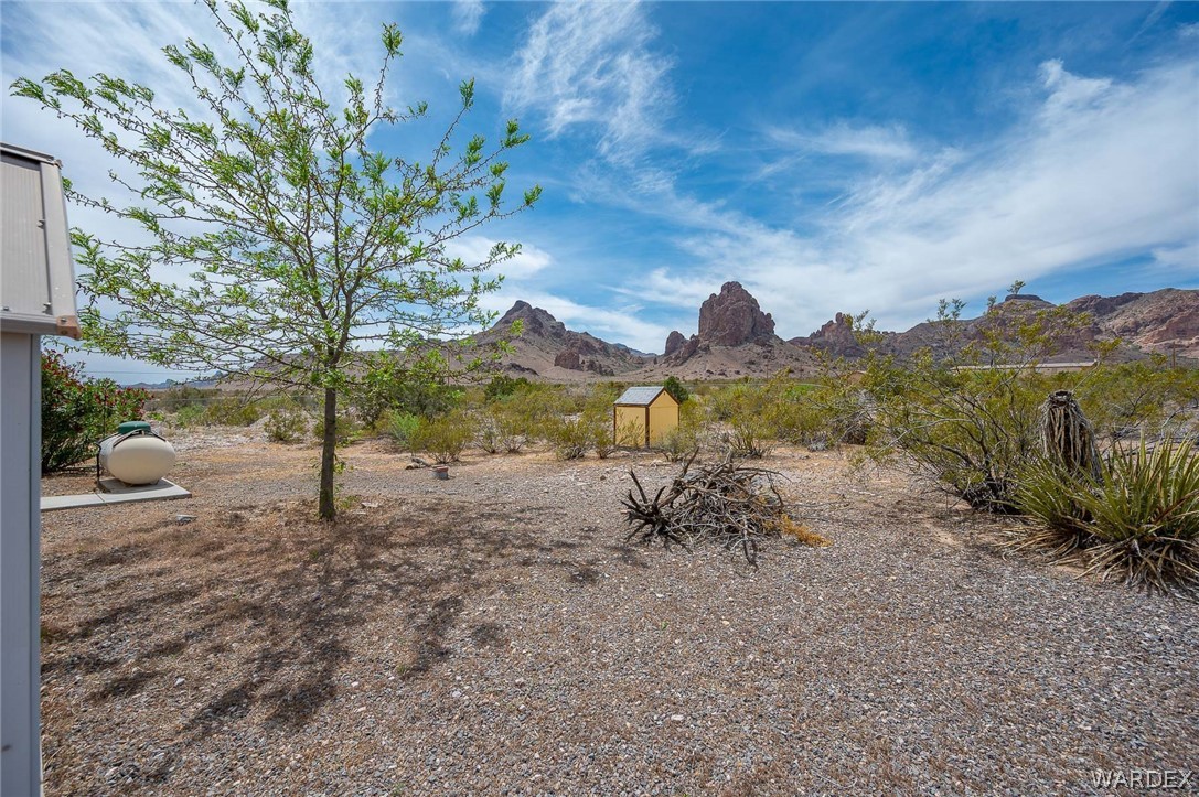 2465 Egar Road Golden Valley, AZ 86413 - Photo 58 of 98 The property features a gravel yard with a tree providing shade, a propane tank, and a small yellow structure