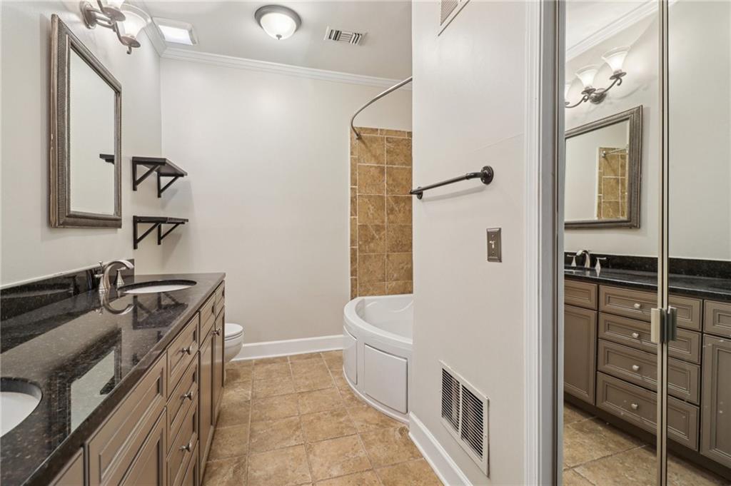 3071 Lenox Road Northeast, Unit 8 Atlanta, GA 30324 - Photo 25 of 50 a bathroom with a granite countertop sink a toilet a mirror and shower