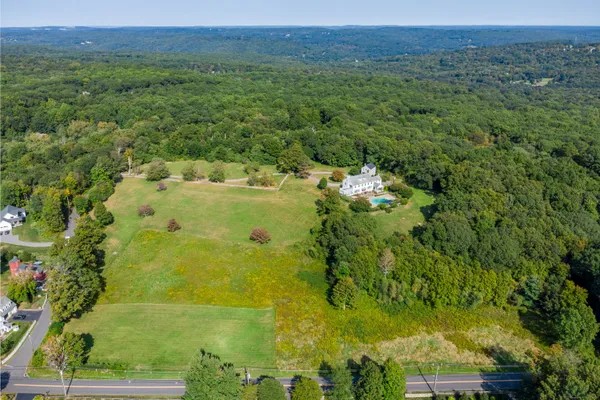 an aerial view of residential houses with outdoor space and trees