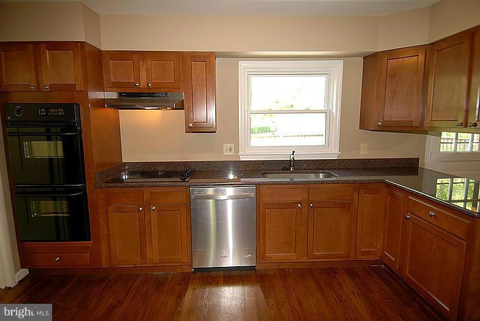 409 Highgate Terrace Silver Spring, MD 20904 - Photo 8 of 30 a kitchen with granite countertop wooden floors wooden cabinets a sink and a window