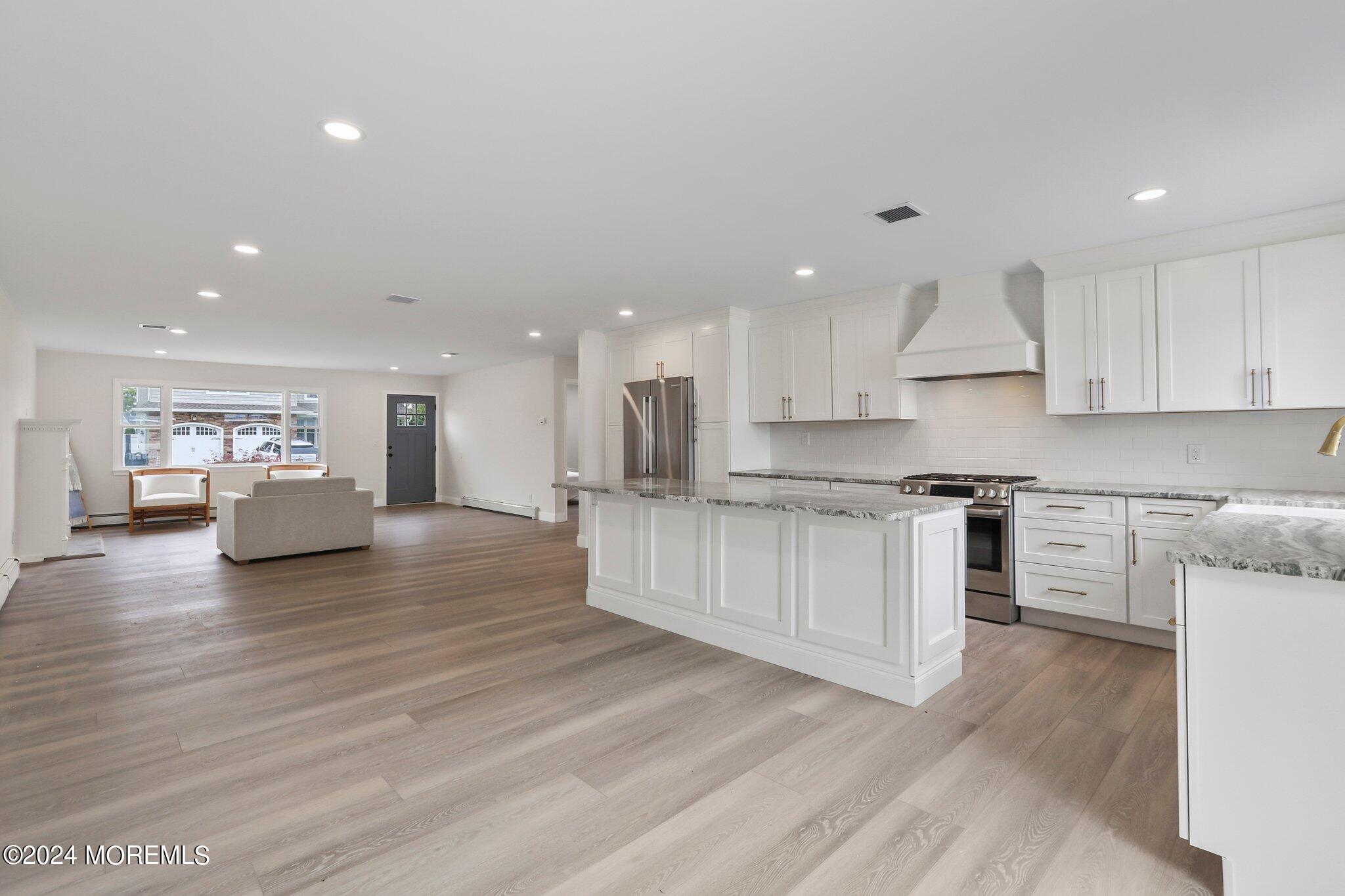 1419 Joseph Street Point Pleasant, NJ 08742 - Photo 4 of 27 a large kitchen with stainless steel appliances granite countertop a large center island a stove a refrigerator white cabinets and wooden floor