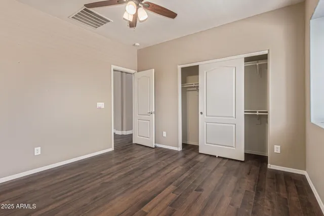 an empty room with wooden floor closet and windows