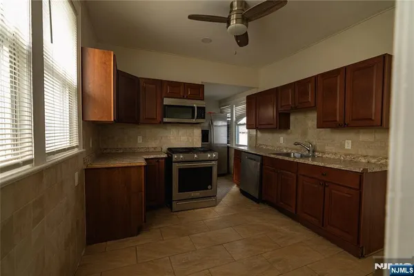 a kitchen with stainless steel appliances granite countertop a stove sink microwave and window
