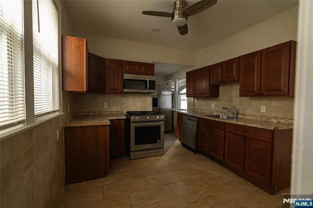 a kitchen with stainless steel appliances granite countertop a stove sink microwave and window