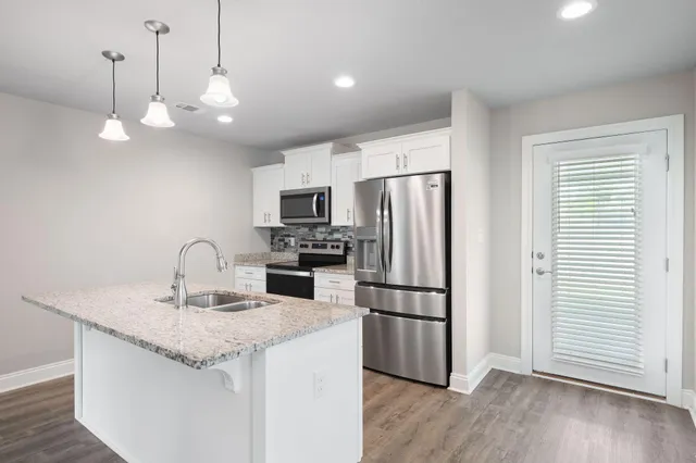 a kitchen with stainless steel appliances white cabinets white stove a microwave and a refrigerator