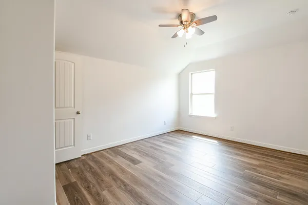 an empty room with wooden floor chandelier fan and windows
