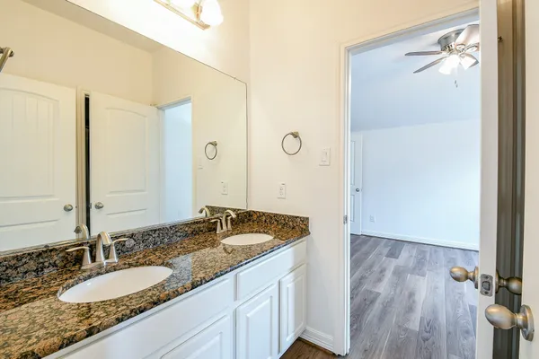 a bathroom with a granite countertop sink a mirror and a shower