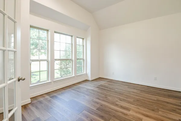 an empty room with wooden floor and windows