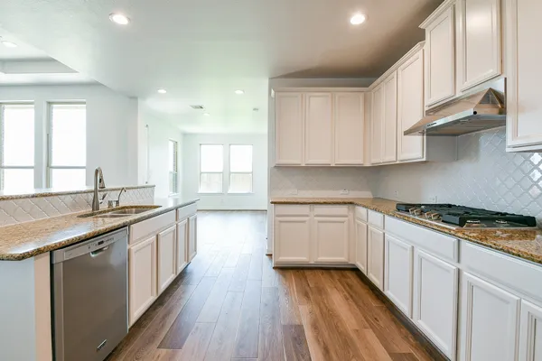 a kitchen with wooden floor sink stove and cabinets