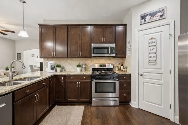 a kitchen with stainless steel appliances granite countertop a stove a sink and a microwave