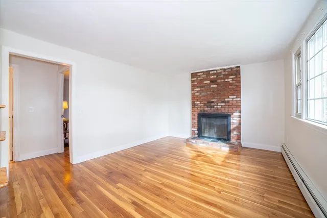 a view of empty room with wooden floor and fireplace