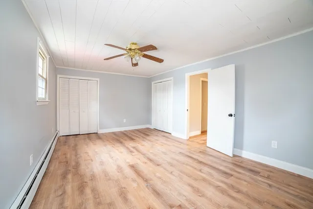 a view of empty room with wooden floor and fan
