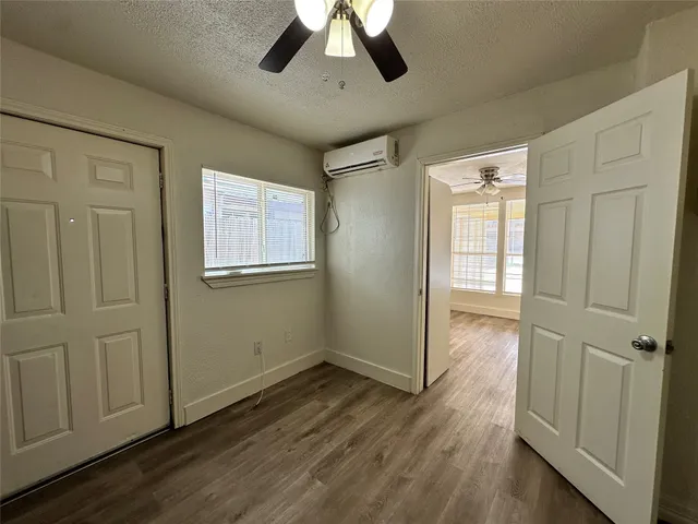 an empty room with wooden floor cabinet and windows