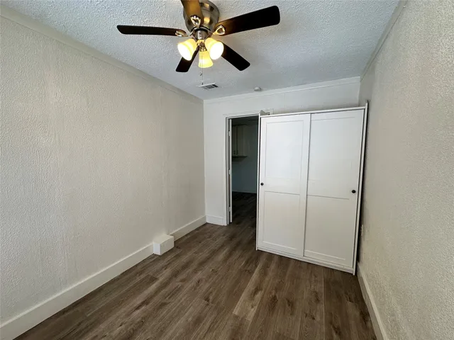 an empty room with wooden floor and ceiling fan