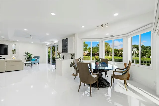 a kitchen with stainless steel appliances kitchen island granite countertop a stove top oven a sink dishwasher and white cabinets with wooden floor