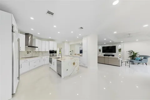 a kitchen with stainless steel appliances kitchen island granite countertop a stove a sink and a refrigerator