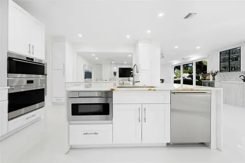 a kitchen with stainless steel appliances kitchen island granite countertop a table chairs sink and cabinets