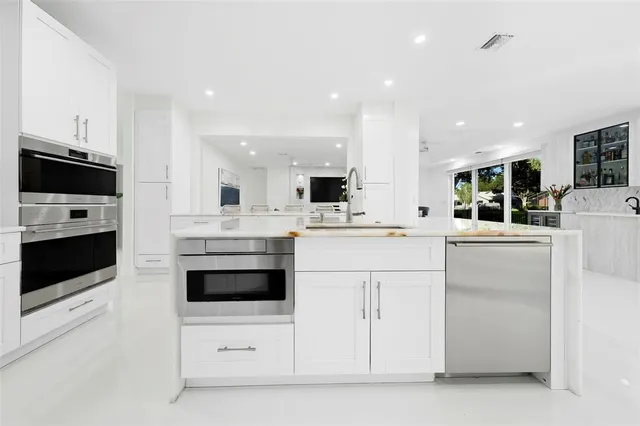 a kitchen with stainless steel appliances kitchen island granite countertop a table chairs sink and cabinets