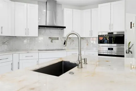 a kitchen with kitchen island granite countertop a sink and white cabinets