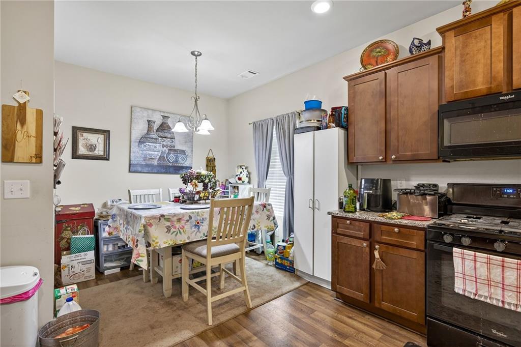 89 Dundee Crossing Dallas, GA 30132 - Photo 13 of 30 a kitchen with stainless steel appliances granite countertop a refrigerator a sink dishwasher a stove and a dining table with wooden floor