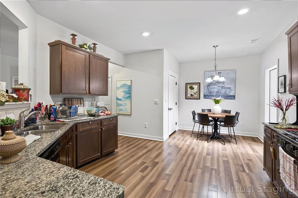 89 Dundee Crossing Dallas, GA 30132 - Photo 14 of 30 a kitchen with stainless steel appliances granite countertop a refrigerator a stove top oven a dining table and chairs with wooden floor