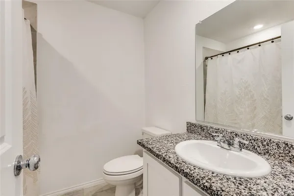 a bathroom with a granite countertop sink toilet and a mirror