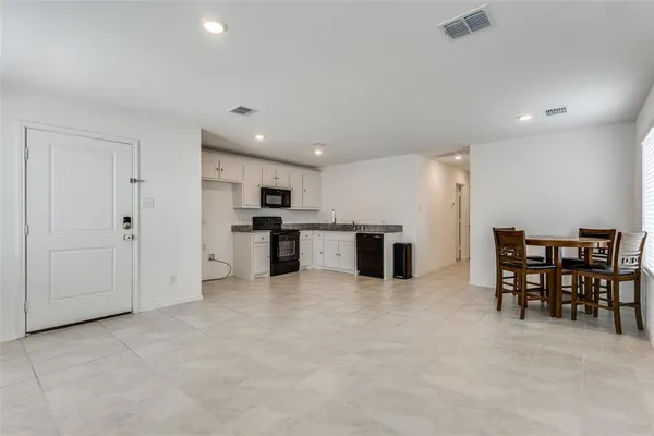 a large white kitchen with a sink and chairs